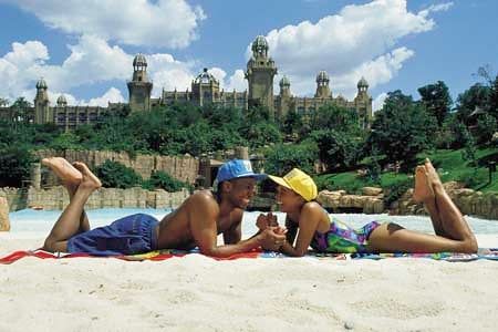 A couple rests on the sandy beach bordering the pool at the Valley of Waves water park in Sun City near Pilanesberg National Park.